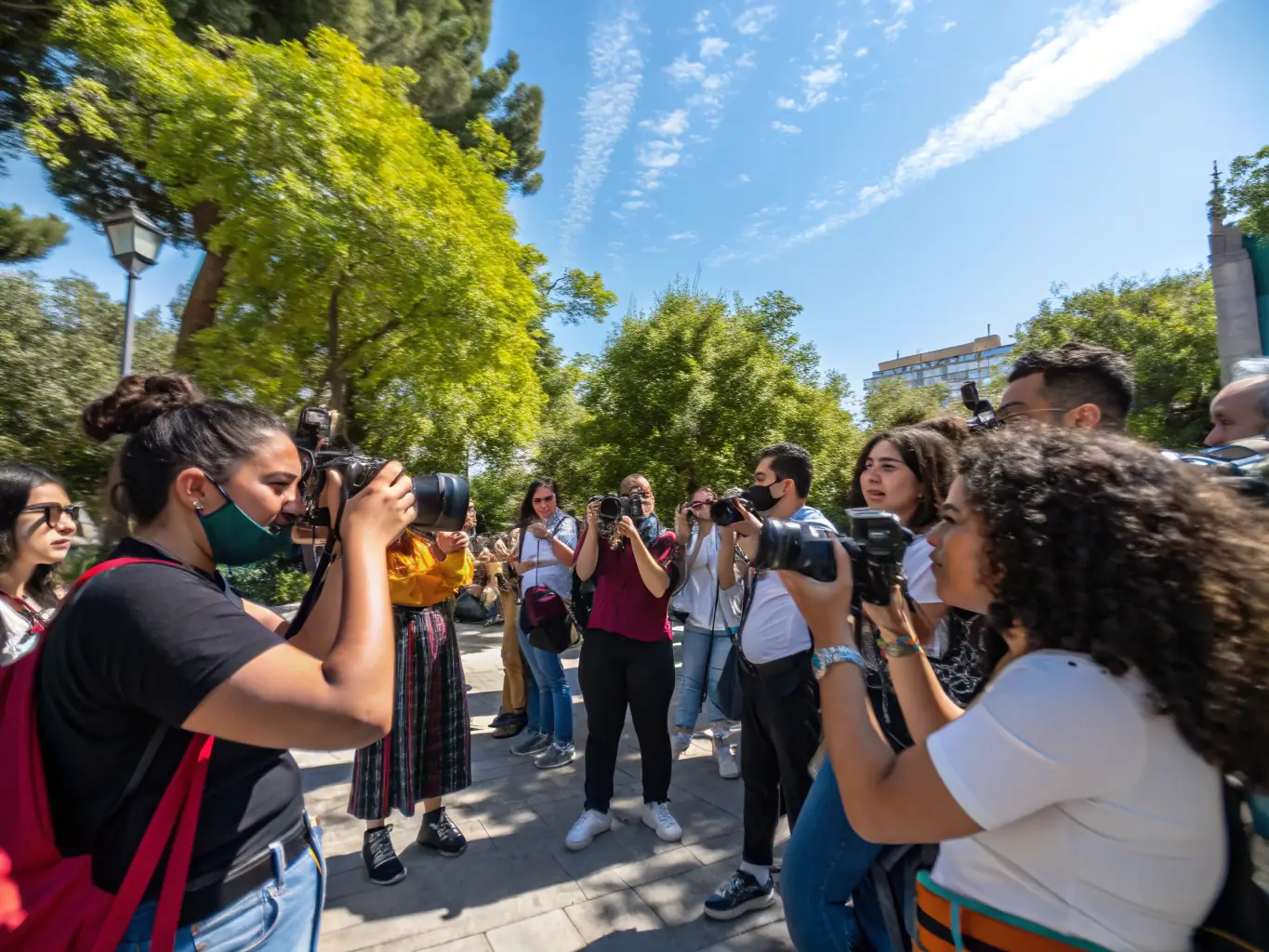 A diverse group of participants engaged in a photography workshop, capturing images outdoors under the guidance of an instructor, with cameras and notebooks in hand.